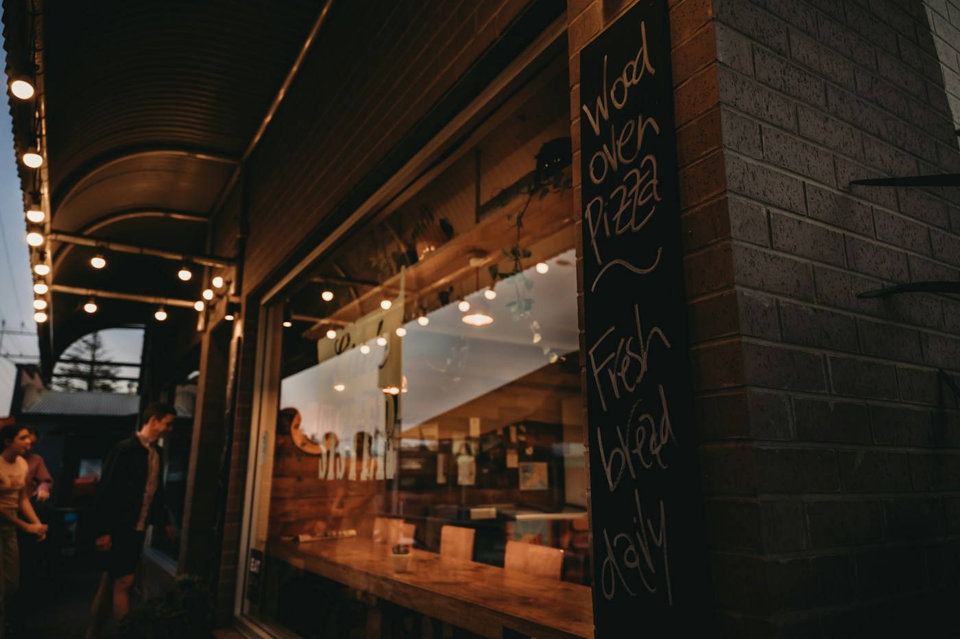 Illustrative restaurant storefront photograph with string lights and a menu board